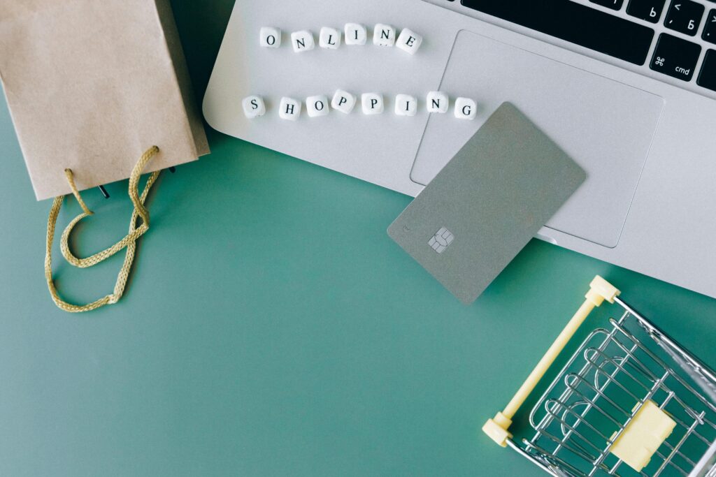pexels-photo-6214365-6214365 Flat lay of online shopping essentials with laptop, card, and shopping cart.